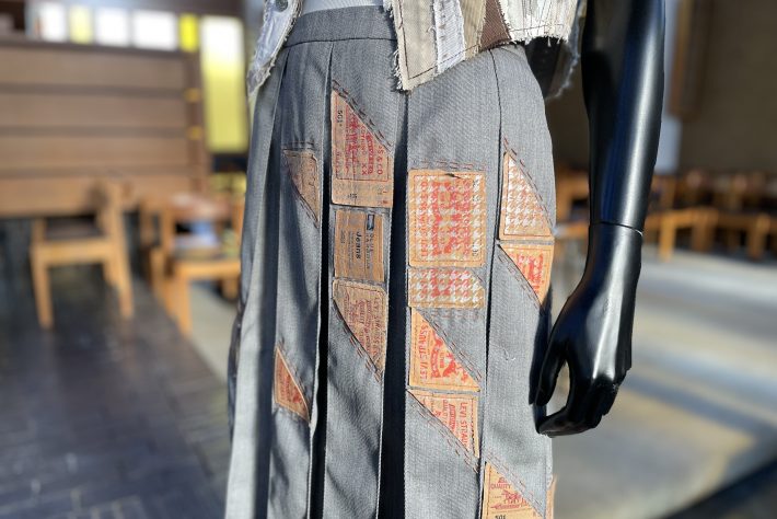 Close-up detail of a skirt made from recycled denim, decorated with old jean labels