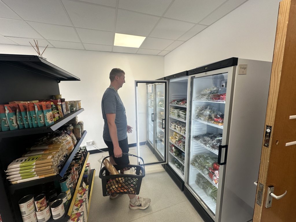 Man opening a fridge with a basket in his hand