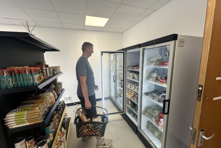 Man opening a fridge with a basket in his hand