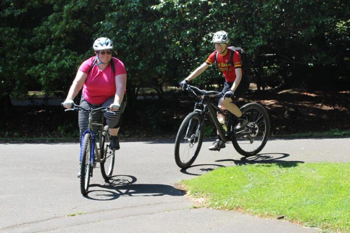 Two people cycling & smiling in sunshine